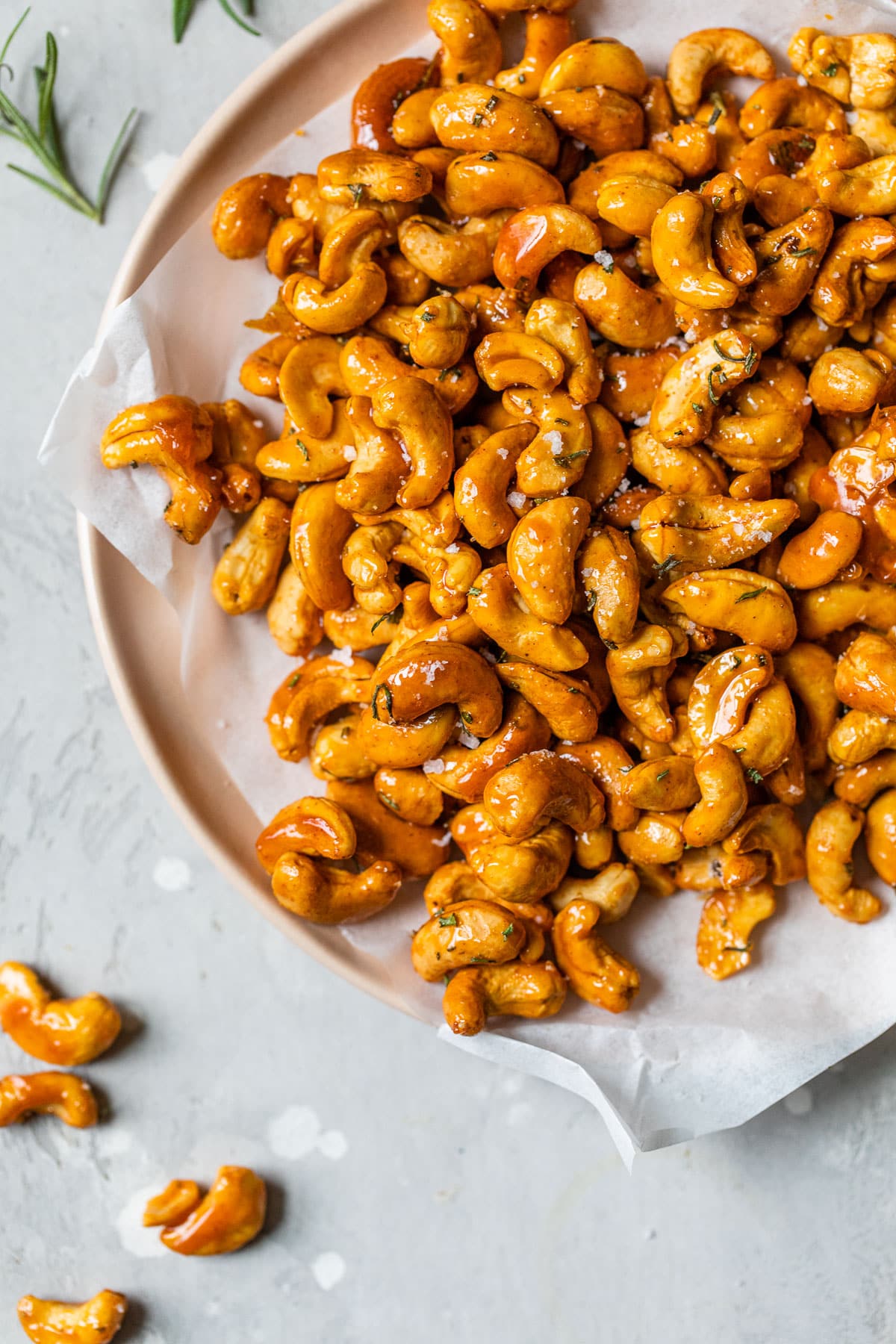 Honey-glazed cashews cooling on parchment, glossy and golden.